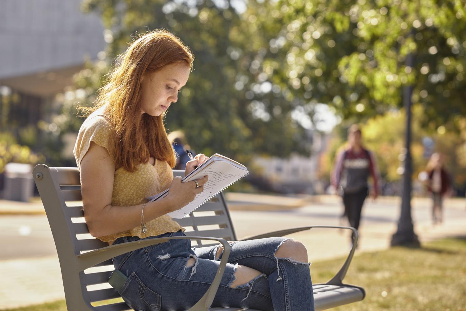 一位<a href='http://lqdk.dzflgg.net'>bv伟德ios下载</a>学院的学生在校园里的长椅上读书.